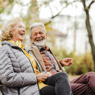 A happy senior couple sitting together on a park bench
